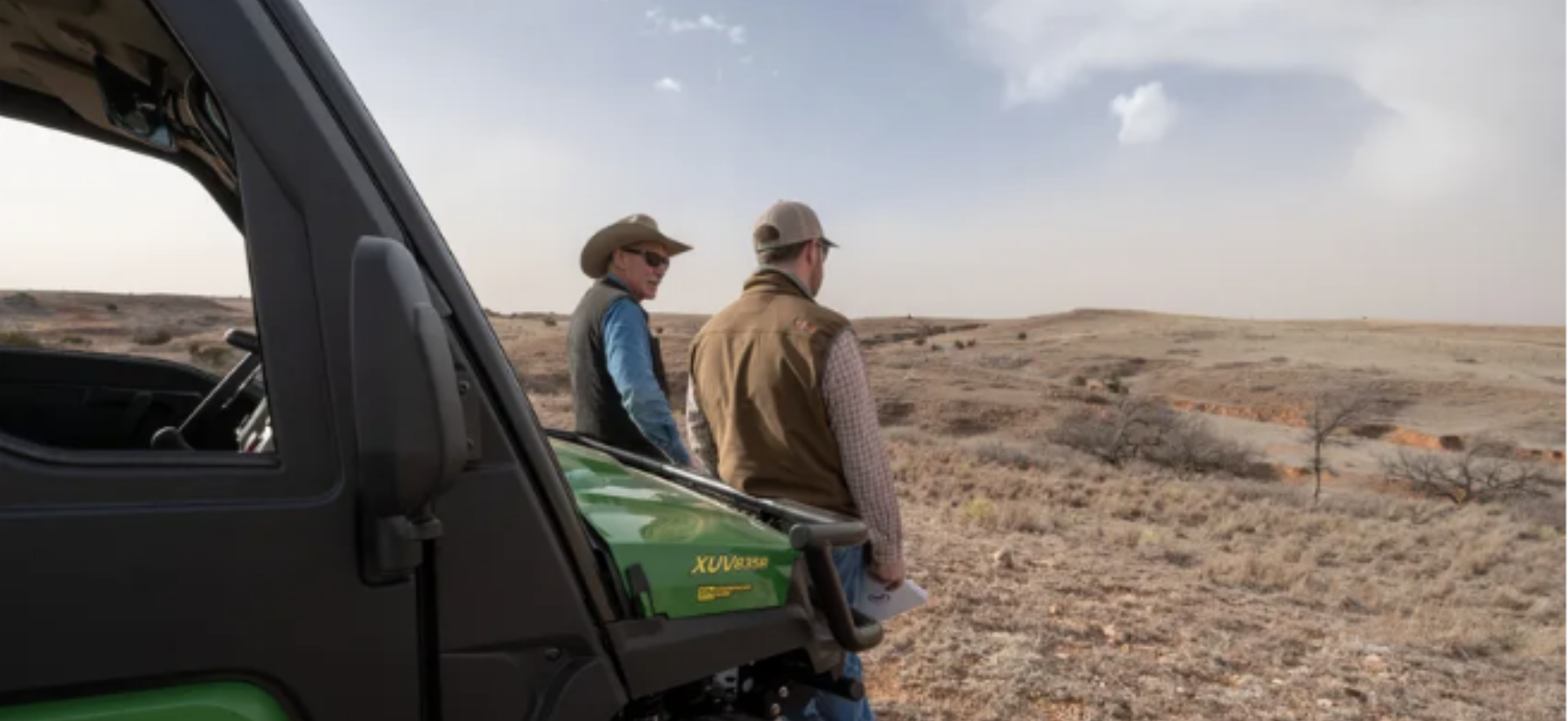 Two people standing in a field in front of a tractor