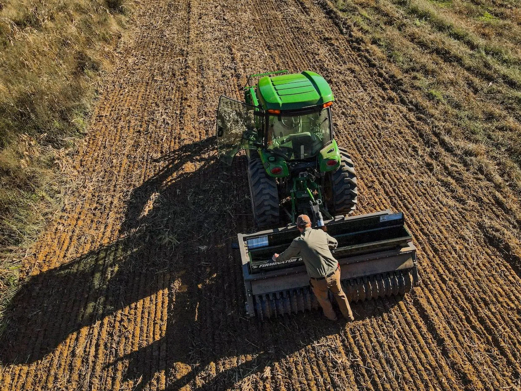 Green John Deere tractor working in agricultural field, illustrating farming operations and internal road systems on rural property