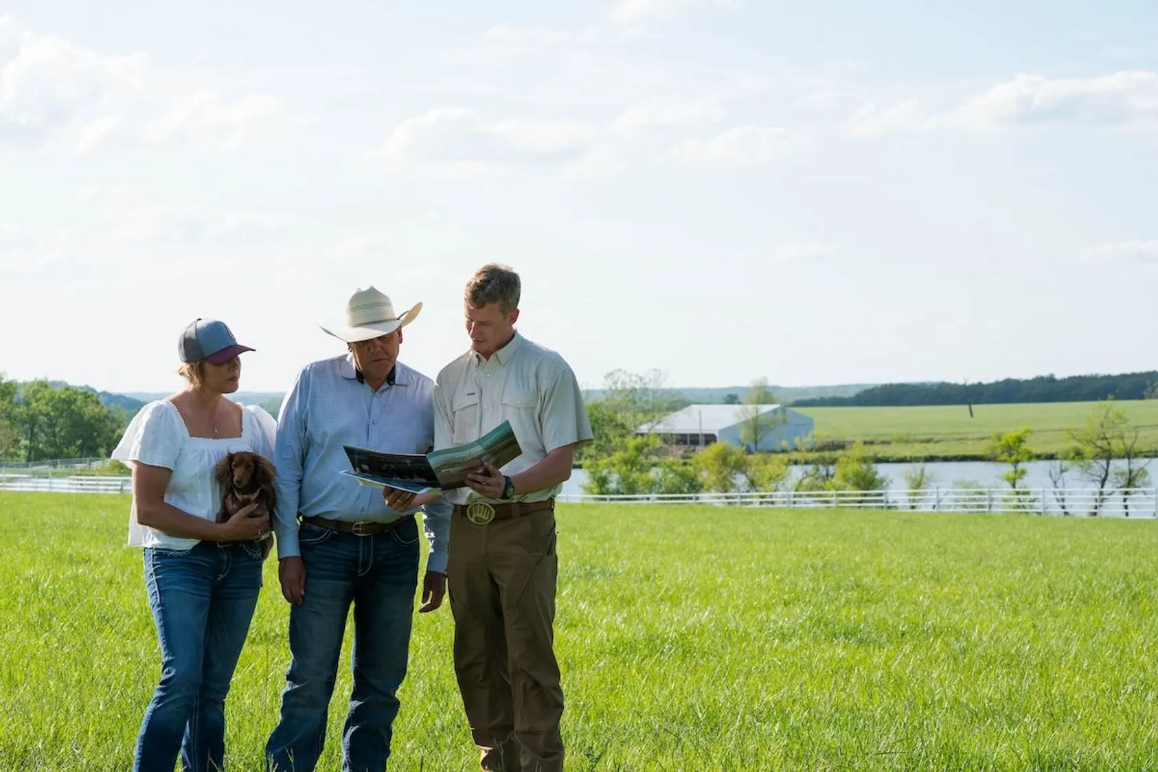 Three men in business attire standing together in grassy area near water feature, showing collaborative approach to land evaluation and client service