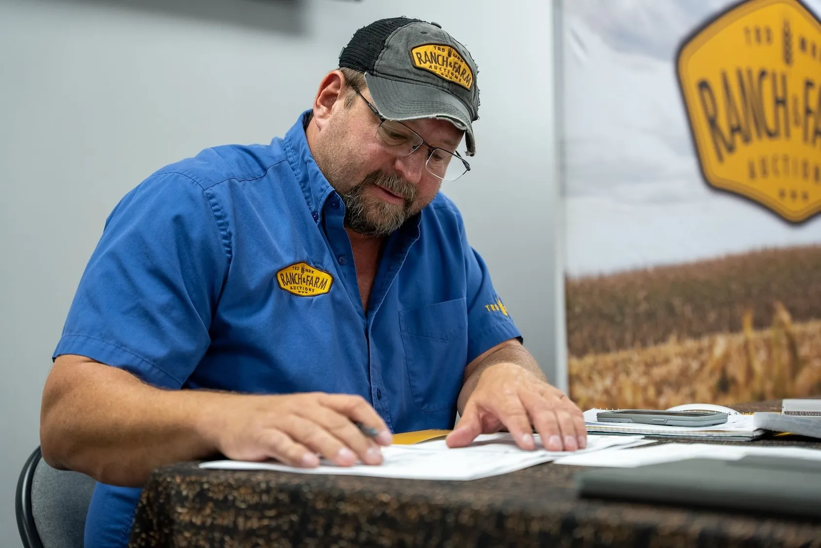 Land specialist in blue shirt working at desk with paperwork, representing professional real estate services for rural property transactions
