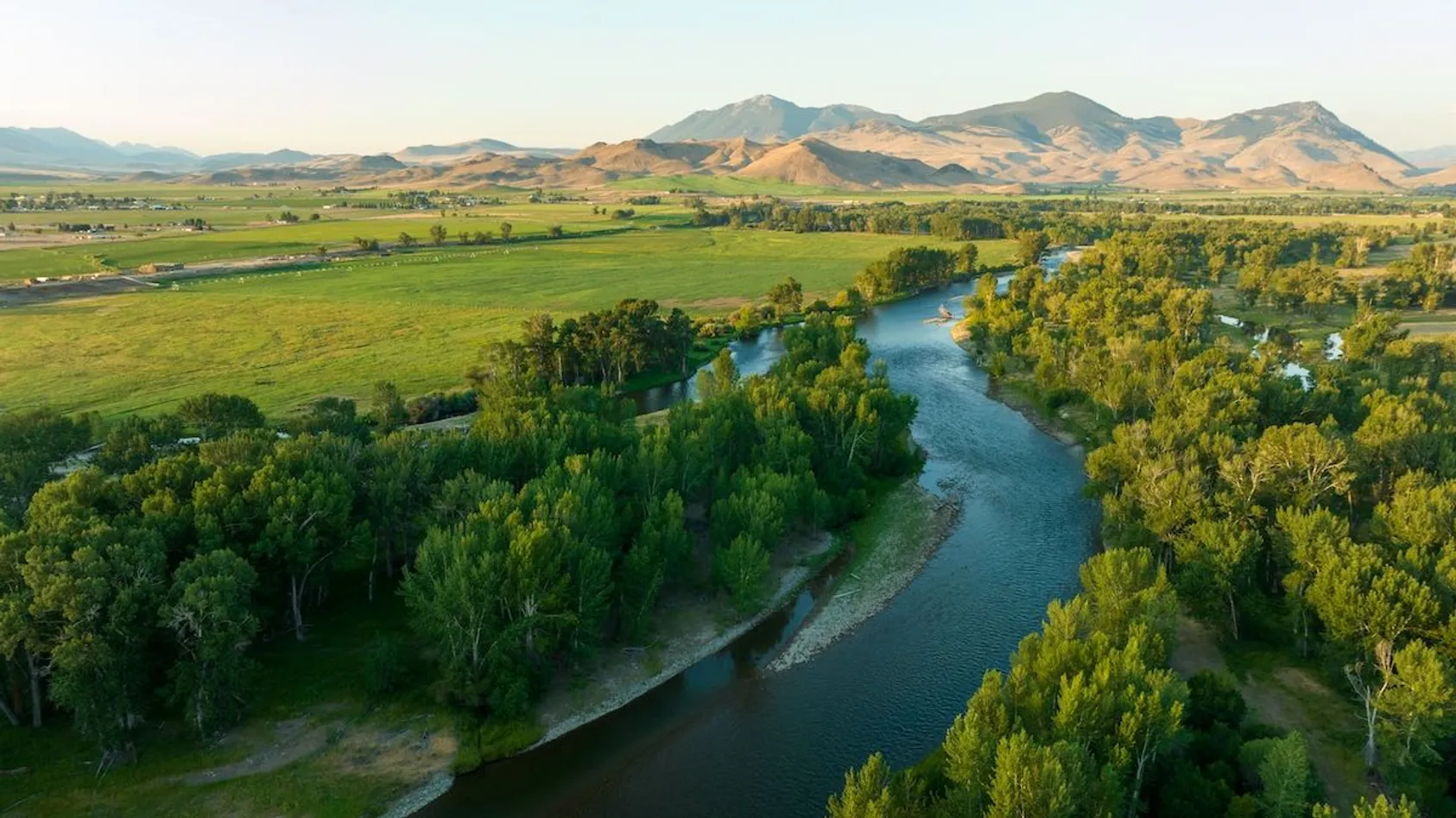 Aerial view of river valley with agricultural fields and forested areas, illustrating diverse terrain and water resources on rural property