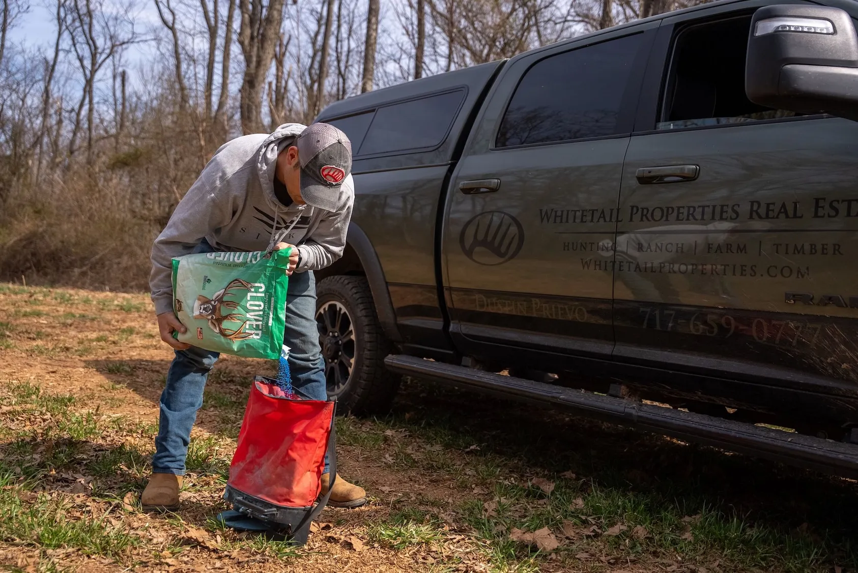 Hunter in camouflage with hunting dog standing next to pickup truck, showing preparation for turkey hunting in the field