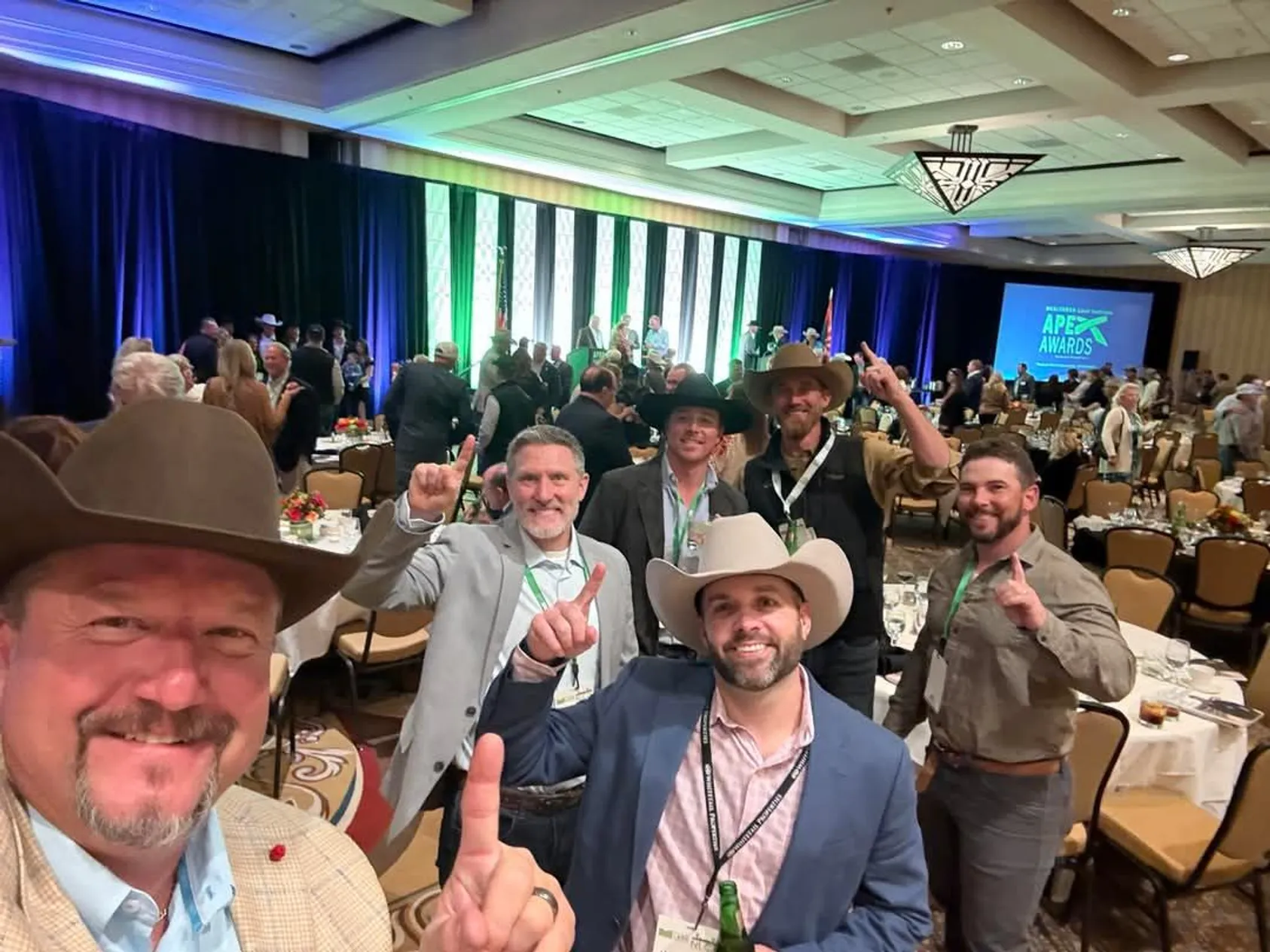 Group photo of Whitetail Properties team members at awards ceremony dinner, men in suits posing together at their table